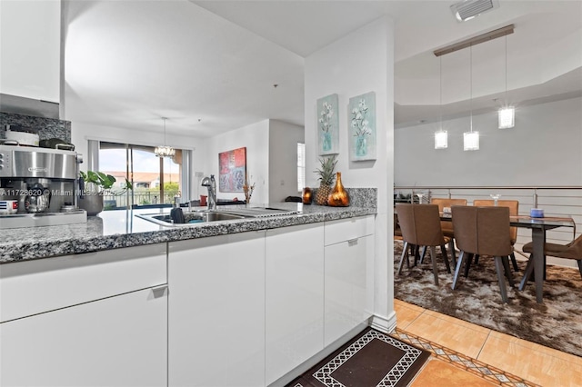 kitchen featuring decorative light fixtures, light tile patterned floors, white cabinets, and sink