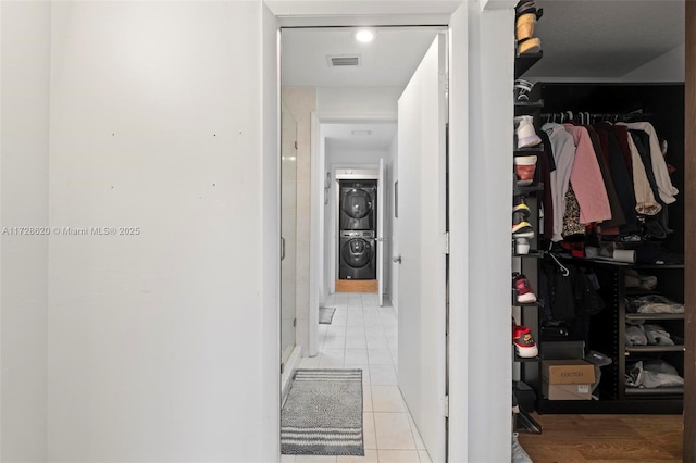 corridor featuring light tile patterned floors and stacked washer / drying machine