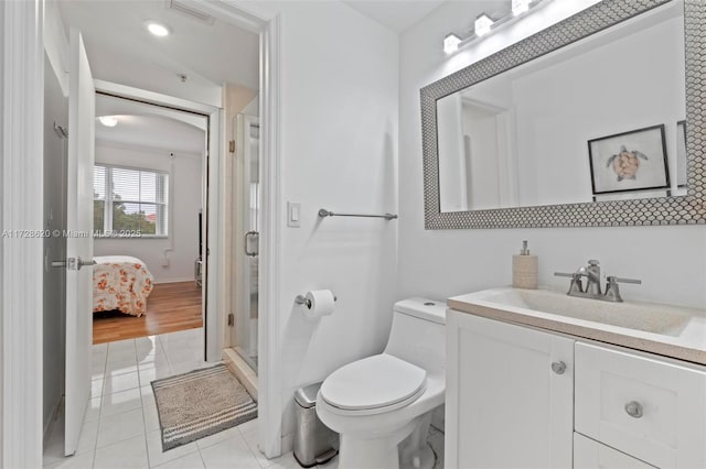 bathroom with toilet, vanity, tile patterned flooring, and a shower with shower door