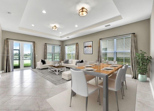 dining area with a wealth of natural light and a tray ceiling