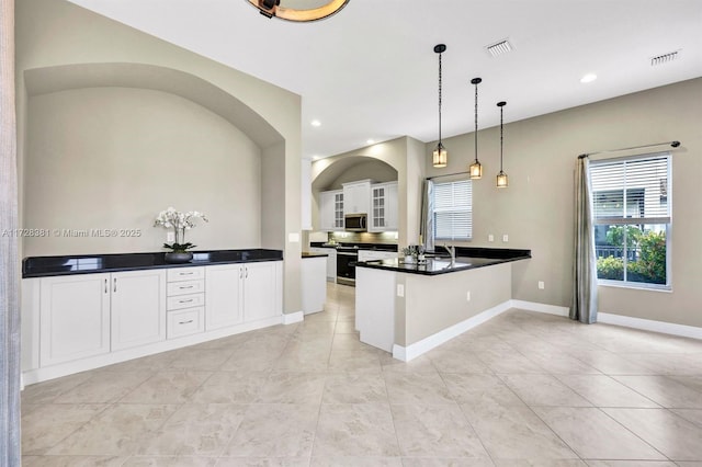 kitchen with kitchen peninsula, appliances with stainless steel finishes, decorative light fixtures, white cabinets, and sink