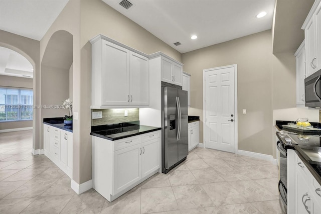 kitchen with light tile patterned floors, backsplash, appliances with stainless steel finishes, and white cabinetry