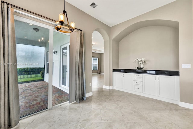 hallway featuring light tile patterned floors and a notable chandelier