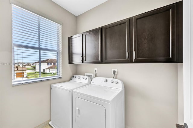 laundry area with a wealth of natural light, separate washer and dryer, and cabinets