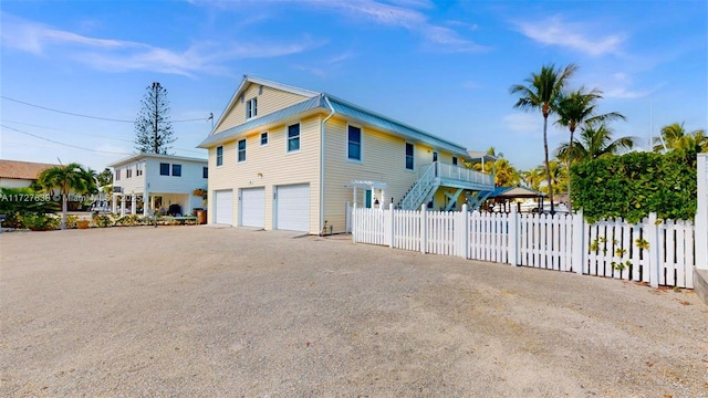 view of side of home with driveway, metal roof, a garage, and fence