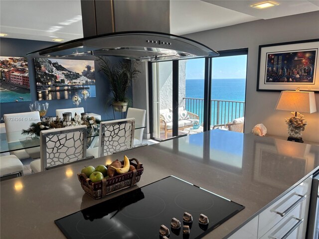1201 S Ocean Dr Unit 2505N, Hollywood, FL 33019 - kitchen with black electric stovetop, white cabinetry, a water view, and island range hood