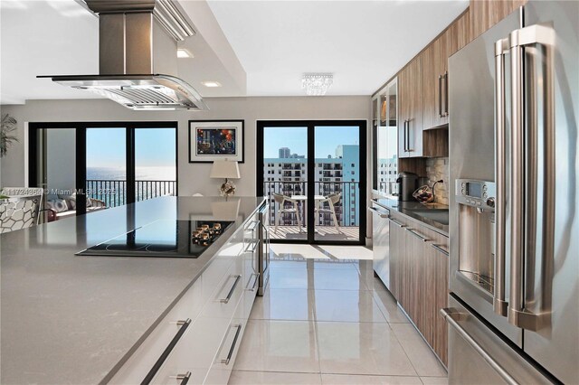 kitchen featuring wall chimney range hood, modern cabinets, black electric cooktop, and stainless steel fridge with ice dispenser