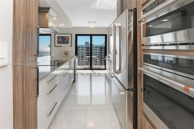 kitchen with a view of city, light tile patterned floors, stainless steel appliances, brown cabinetry, and modern cabinets