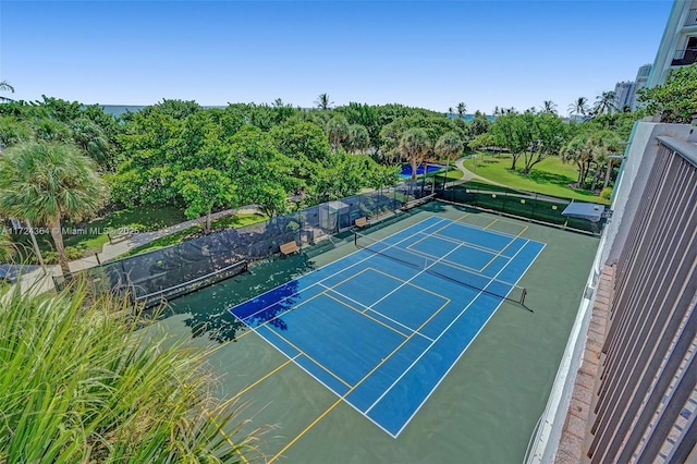 view of tennis court featuring a water view and fence