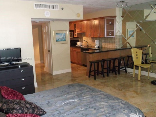 kitchen featuring stainless steel dishwasher, a breakfast bar, kitchen peninsula, decorative backsplash, and sink