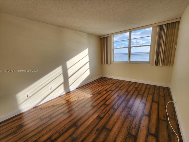 unfurnished room featuring dark hardwood / wood-style floors and a textured ceiling