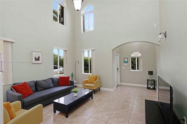 living room with a towering ceiling, a healthy amount of sunlight, and light tile patterned floors