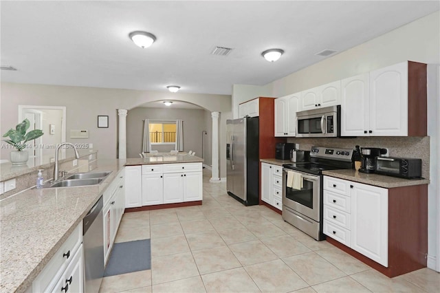 kitchen with stainless steel appliances, sink, white cabinets, and ornate columns