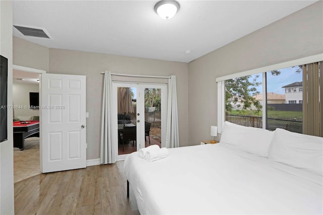 bedroom with access to outside, light wood-type flooring, and french doors