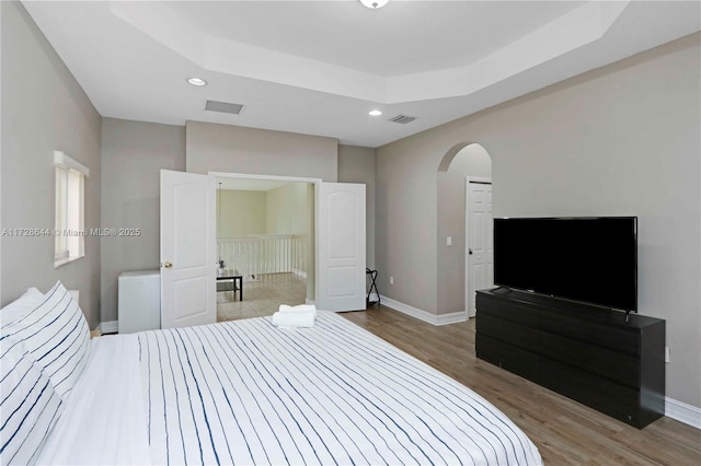 bedroom featuring hardwood / wood-style flooring and a tray ceiling