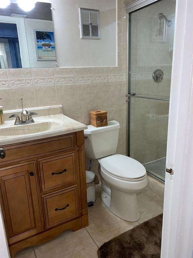 bathroom with toilet, vanity, tile patterned flooring, tile walls, and a shower with door