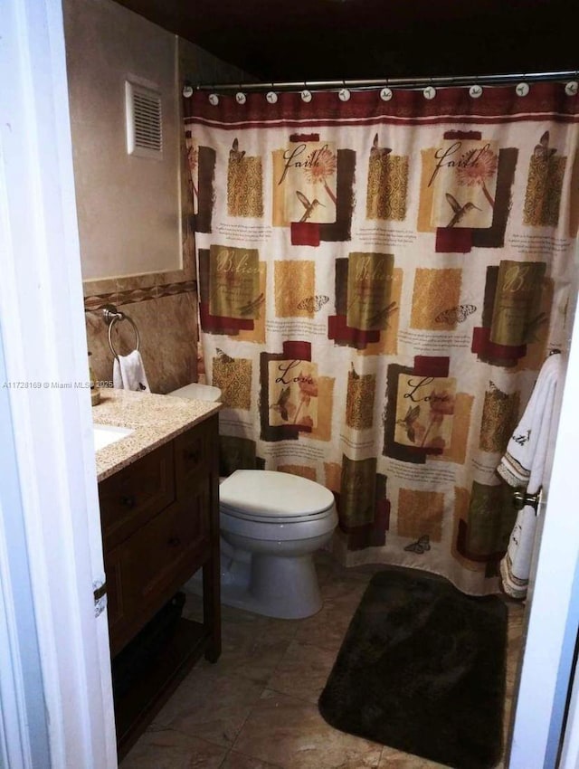 bathroom featuring toilet, vanity, tile walls, and curtained shower