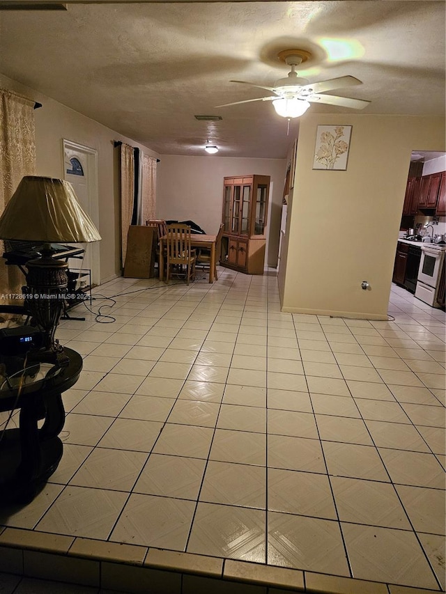 unfurnished living room featuring light tile patterned flooring, ceiling fan, and a textured ceiling