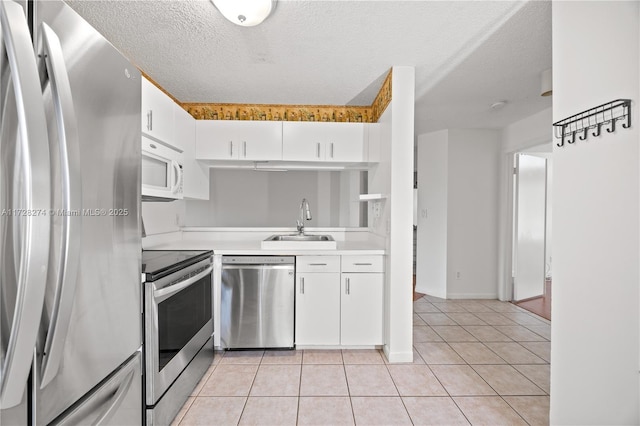 kitchen featuring sink, stainless steel appliances, a textured ceiling, white cabinets, and light tile patterned flooring