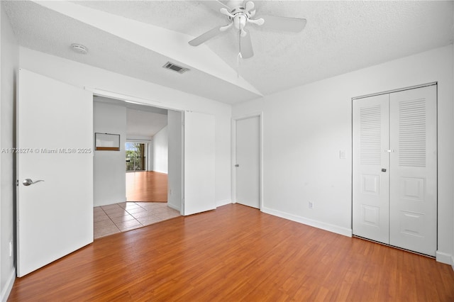 unfurnished bedroom with vaulted ceiling, ceiling fan, a textured ceiling, and hardwood / wood-style flooring