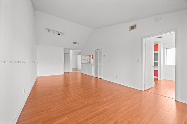 empty room with vaulted ceiling and light hardwood / wood-style floors