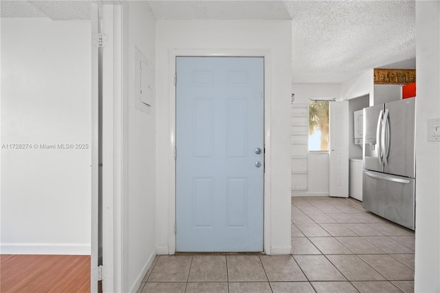 interior space featuring a textured ceiling, light tile patterned floors, and stainless steel fridge with ice dispenser