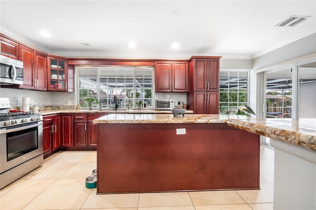 kitchen featuring light tile patterned floors, stainless steel appliances, ornamental molding, and light stone countertops