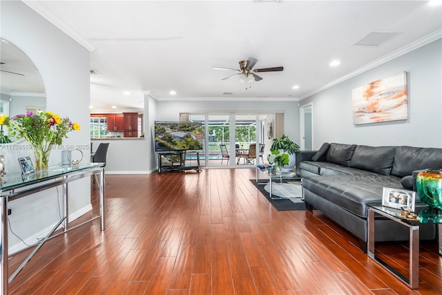 living room with dark wood-type flooring, crown molding, and ceiling fan