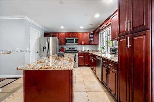 kitchen featuring a kitchen island, crown molding, light stone countertops, appliances with stainless steel finishes, and light tile patterned floors