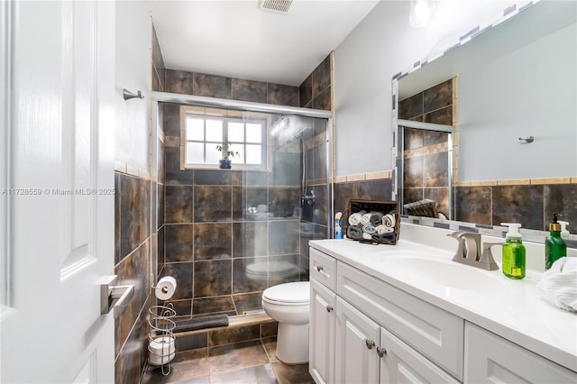 bathroom with toilet, tile walls, tile patterned floors, an enclosed shower, and vanity