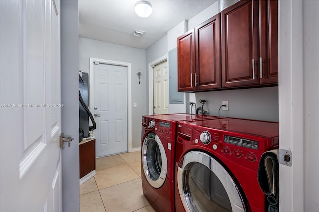 clothes washing area with light tile patterned floors, a textured ceiling, washing machine and clothes dryer, and cabinets