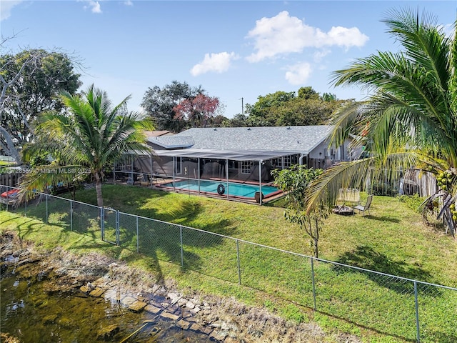 back of house with a lanai, a yard, and a fenced in pool