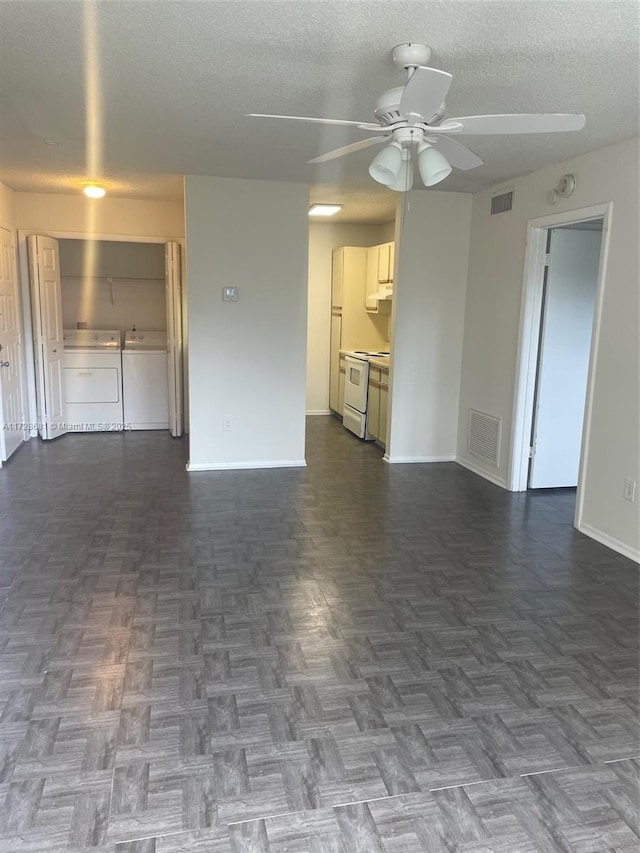 unfurnished living room featuring a textured ceiling, ceiling fan, dark parquet floors, and washing machine and clothes dryer