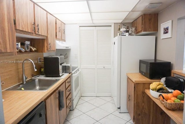 kitchen with a paneled ceiling, light tile patterned floors, sink, and black appliances