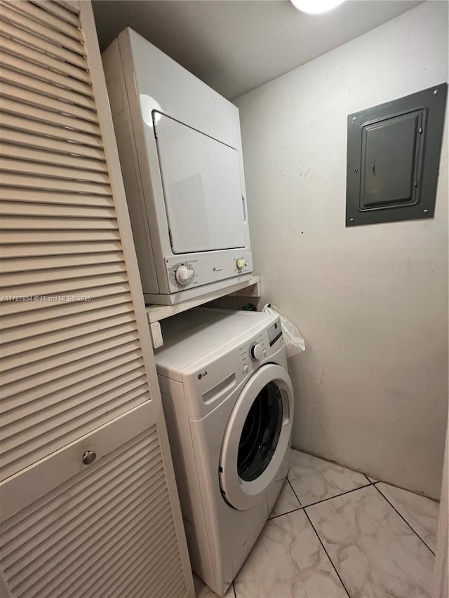 laundry area featuring electric panel and stacked washer / drying machine