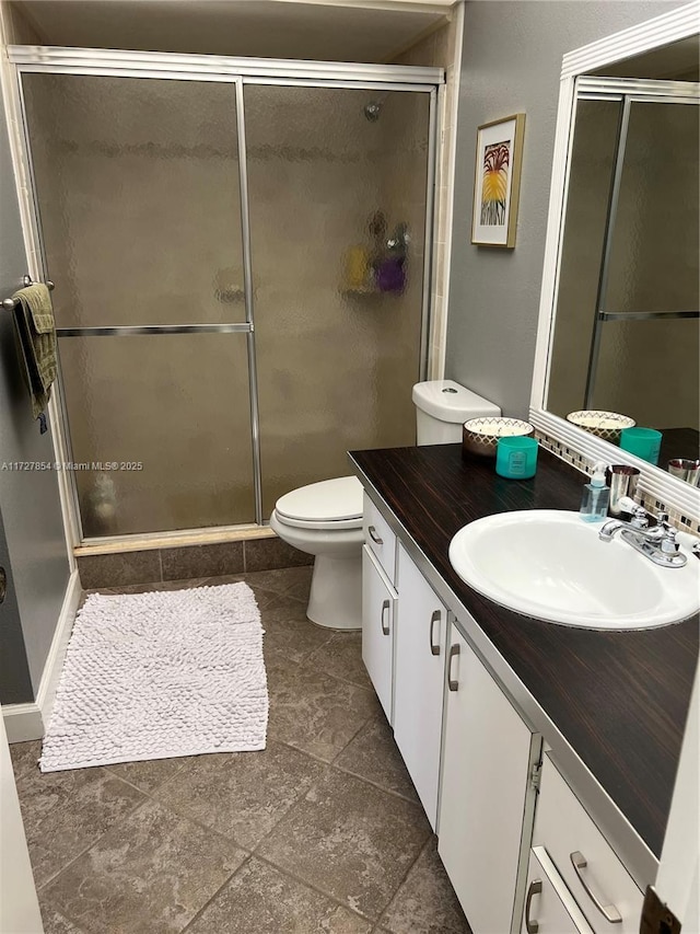 bathroom featuring a shower with door, toilet, and vanity