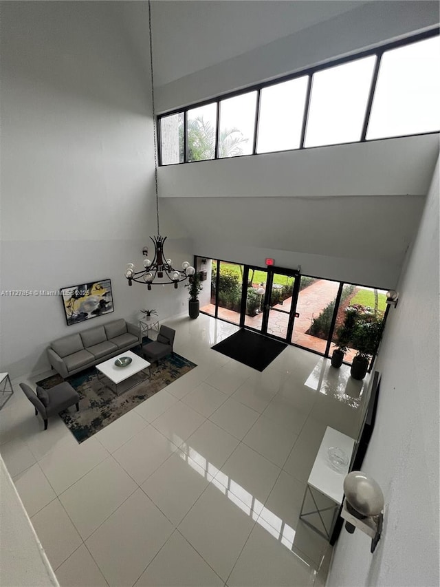 unfurnished living room with an inviting chandelier, tile patterned flooring, and a towering ceiling