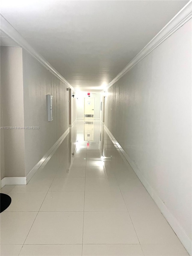 corridor with light tile patterned floors and crown molding