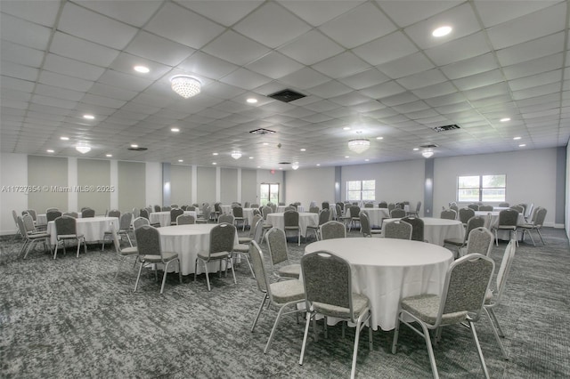 dining space with a drop ceiling and dark colored carpet