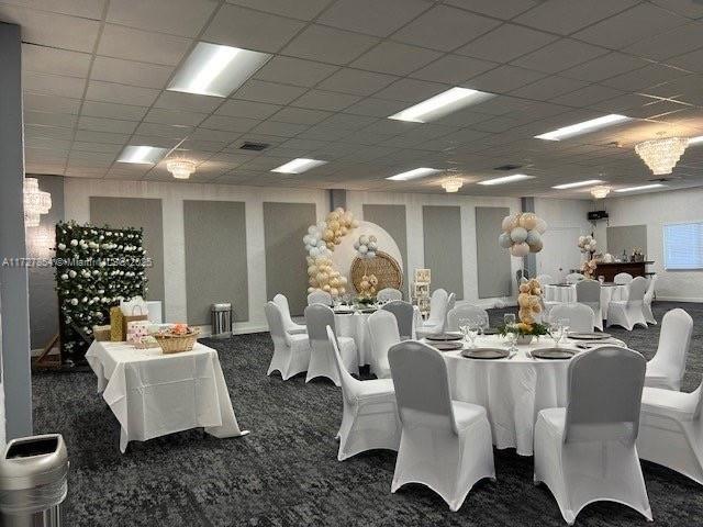 carpeted dining room with a paneled ceiling