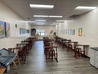 dining space with a drop ceiling and hardwood / wood-style floors