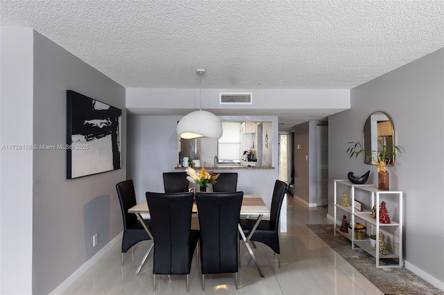 tiled dining space featuring sink and a textured ceiling