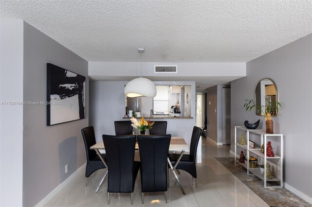 tiled dining area featuring sink and a textured ceiling