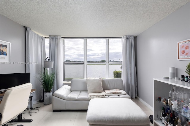 living room with a water view, expansive windows, and a textured ceiling