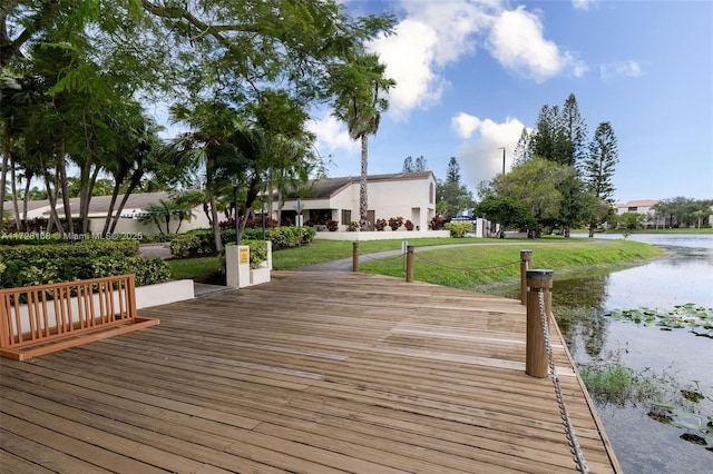 view of dock with a lawn and a water view