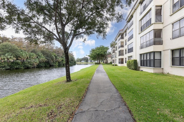 surrounding community with a water view and a yard