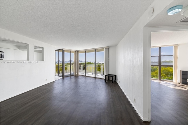 empty room with floor to ceiling windows, a textured ceiling, and dark hardwood / wood-style flooring