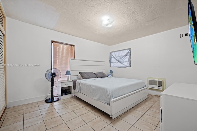 bedroom featuring a textured ceiling, light tile patterned floors, and a wall mounted air conditioner