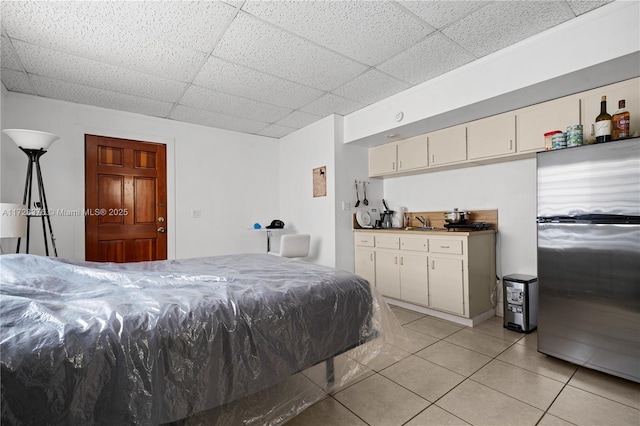 tiled bedroom featuring a paneled ceiling and stainless steel fridge