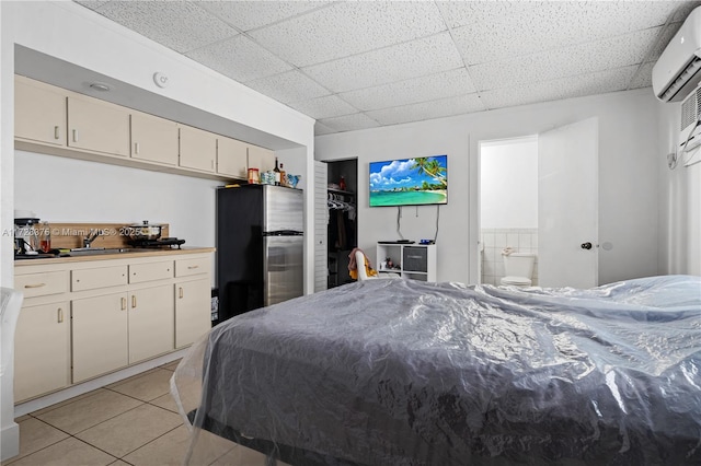 tiled bedroom with an AC wall unit, sink, a drop ceiling, and stainless steel refrigerator